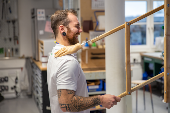 Orthopädietechniker klopft sich lächelnd selbst mit einer Silikon Hand auf der Schulter.  | © Pohlig GmbH