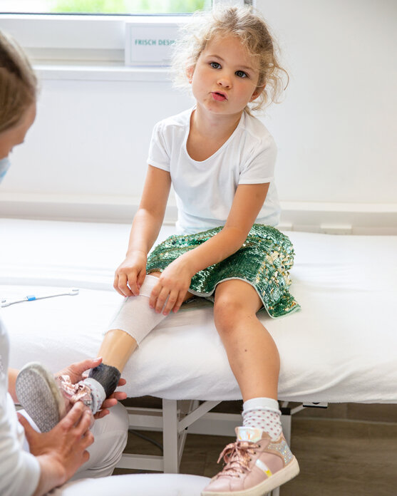 Orthopädietechnikerin zieht Mädchen Orthoprothese an | © Pohlig GmbH