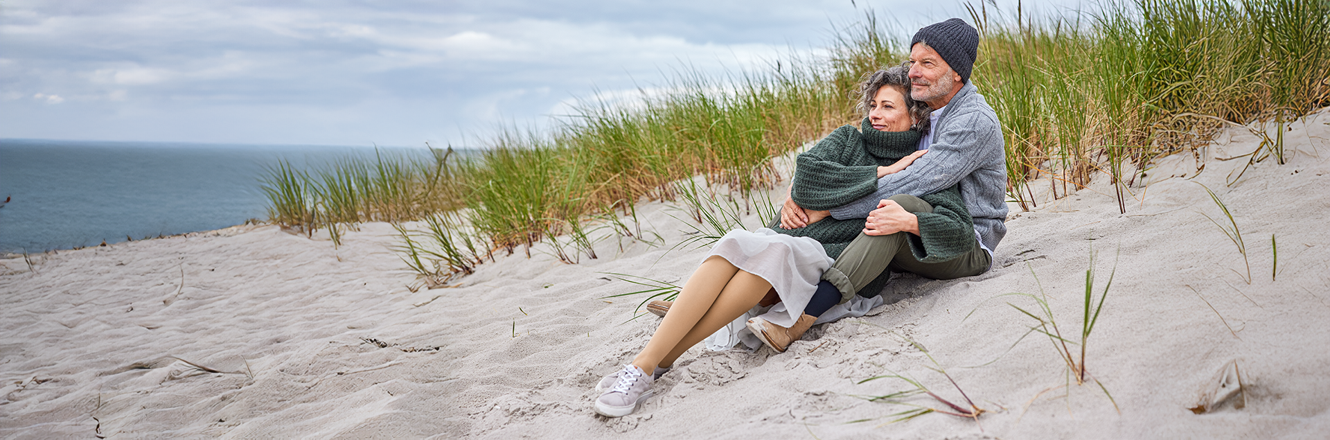 Paar kuschelt am Strand und trägt Kompressionsstrümpfe | © Medi