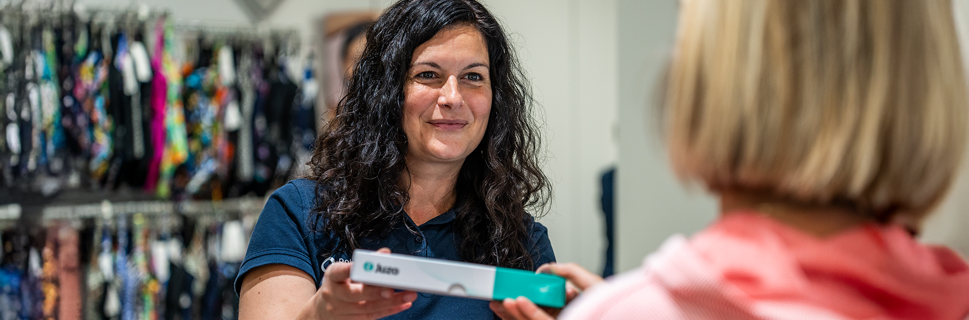 Sanitätshausmitarbeiter reicht Kundin Kompressionsstrümpfe über die Theke | © Pohlig GmbH